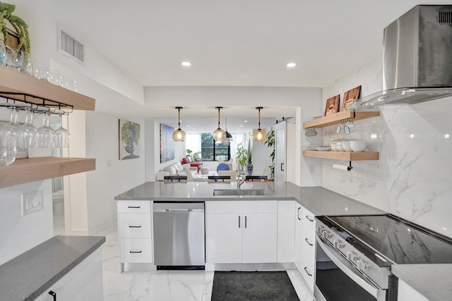 kitchen featuring white cabinets, sink, wall chimney exhaust hood, decorative light fixtures, and stainless steel appliances