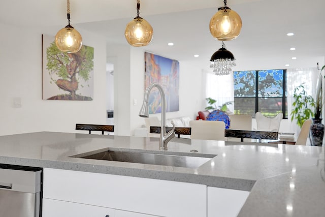 kitchen with white cabinets, light stone counters, sink, decorative light fixtures, and dishwasher