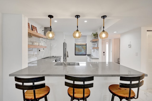 kitchen with pendant lighting, a breakfast bar, kitchen peninsula, and stainless steel refrigerator