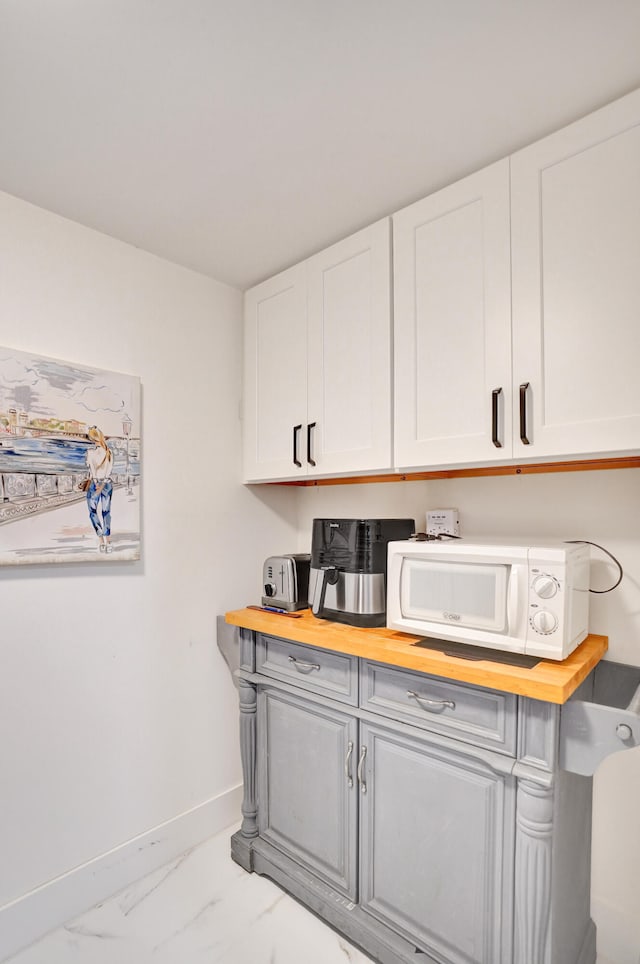 kitchen featuring butcher block countertops and white cabinets