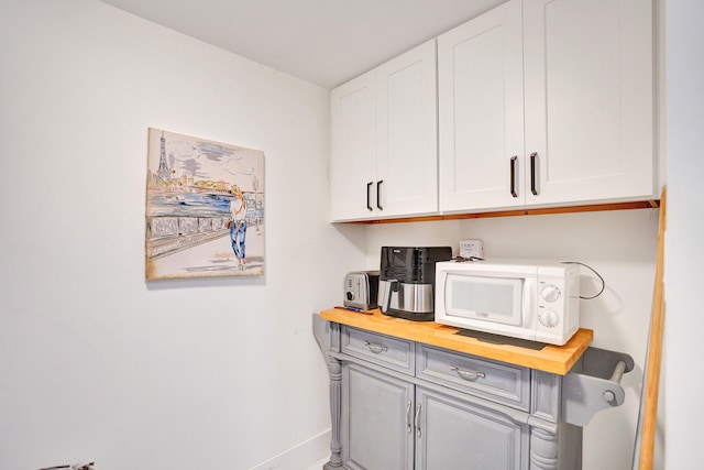 bar with white cabinets and butcher block counters