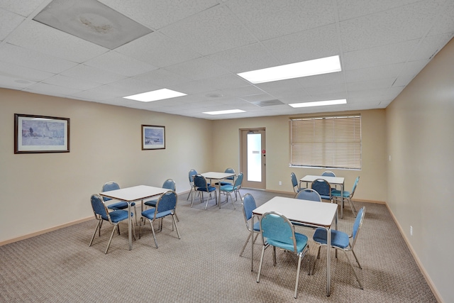 carpeted dining area with a paneled ceiling