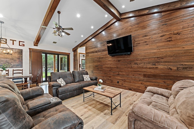 living room featuring high vaulted ceiling, ceiling fan with notable chandelier, wooden walls, beamed ceiling, and light hardwood / wood-style floors