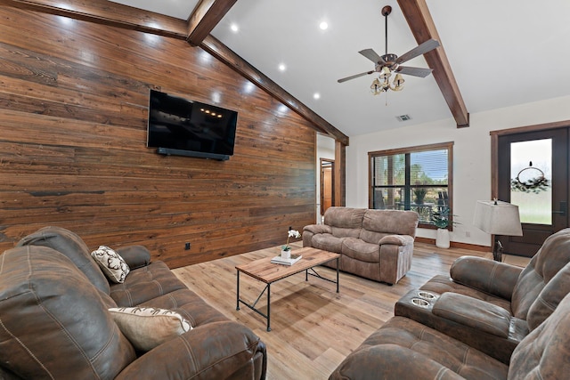 living room with beamed ceiling, light hardwood / wood-style flooring, ceiling fan, and wood walls