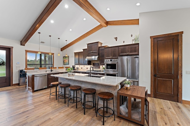 kitchen with appliances with stainless steel finishes, backsplash, sink, decorative light fixtures, and a center island