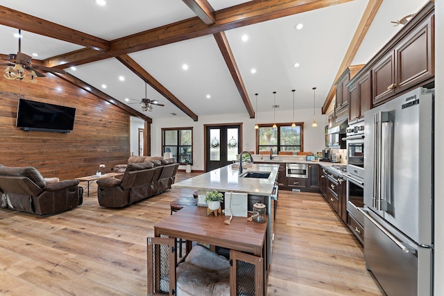 kitchen featuring dark brown cabinetry, sink, stainless steel appliances, pendant lighting, and wooden walls