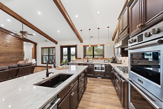 kitchen with french doors, light stone counters, sink, pendant lighting, and beam ceiling