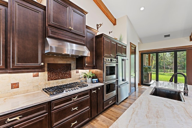 kitchen with sink, stainless steel appliances, vaulted ceiling with beams, backsplash, and exhaust hood