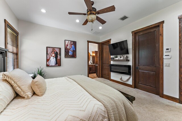 bedroom featuring sink, ceiling fan, light colored carpet, and ensuite bathroom