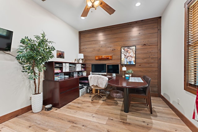 office area featuring light wood-type flooring, vaulted ceiling, ceiling fan, and wooden walls