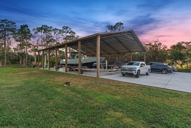 parking at dusk featuring a lawn and a carport