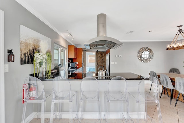 kitchen featuring island exhaust hood, kitchen peninsula, crown molding, light tile patterned floors, and a barn door