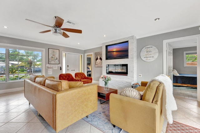 tiled living room featuring ceiling fan, a fireplace, and ornamental molding