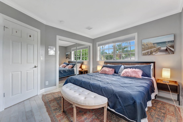 bedroom with hardwood / wood-style flooring, crown molding, and a closet