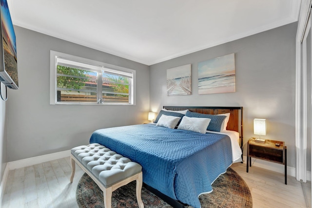 bedroom with light wood-type flooring and crown molding