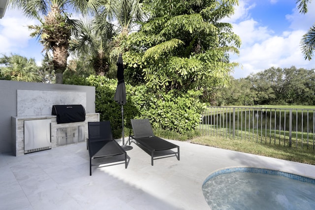 view of patio featuring an outdoor kitchen, a water view, and grilling area