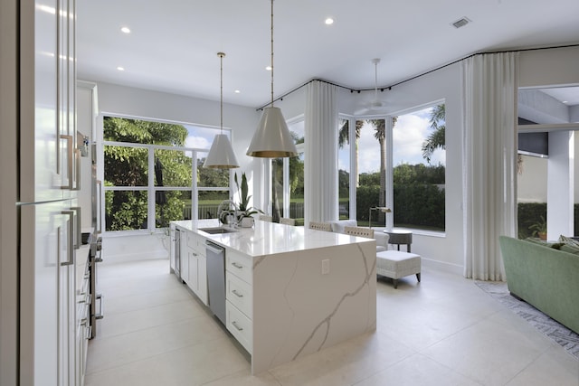 kitchen with sink, white refrigerator, a center island with sink, white cabinets, and hanging light fixtures