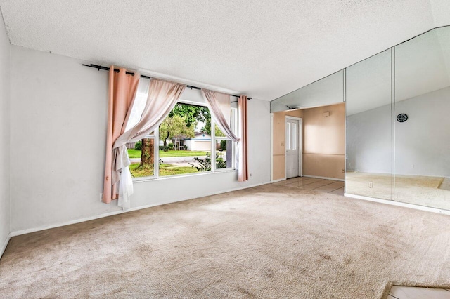 empty room with a textured ceiling, carpet, and lofted ceiling