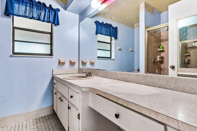 bathroom featuring vanity, tile patterned flooring, and a tile shower