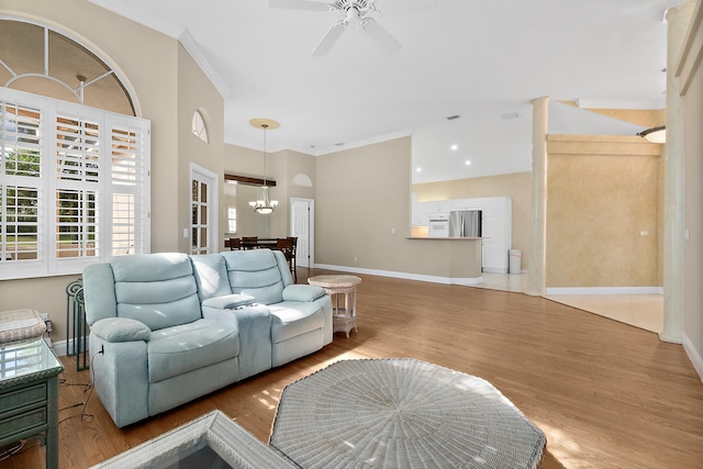 living room with wood-type flooring, ceiling fan with notable chandelier, and crown molding