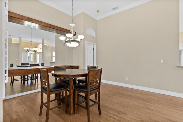 dining room with ornamental molding, wood-type flooring, and an inviting chandelier