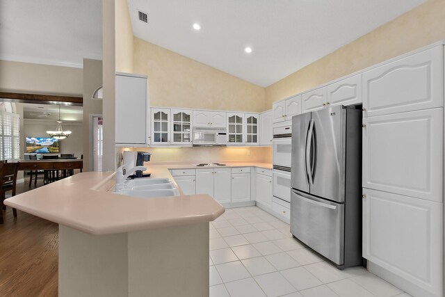 kitchen featuring sink, an inviting chandelier, white appliances, white cabinets, and pendant lighting