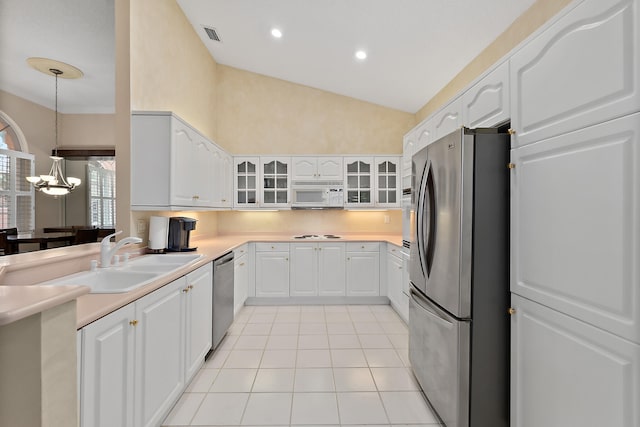 kitchen featuring stainless steel appliances, white cabinetry, sink, decorative light fixtures, and lofted ceiling