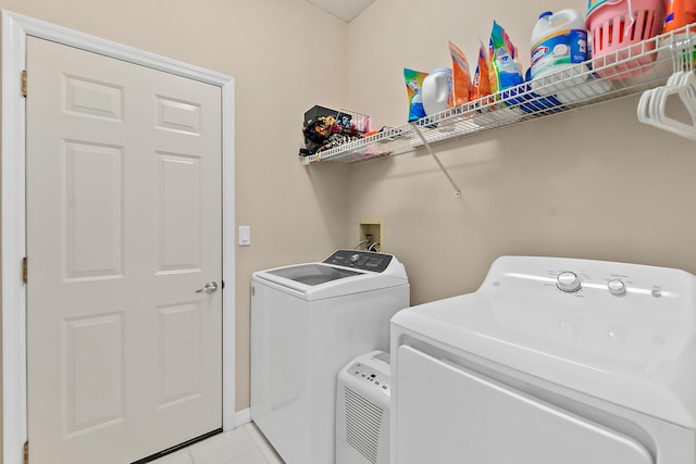 clothes washing area with light tile patterned flooring and washer and clothes dryer