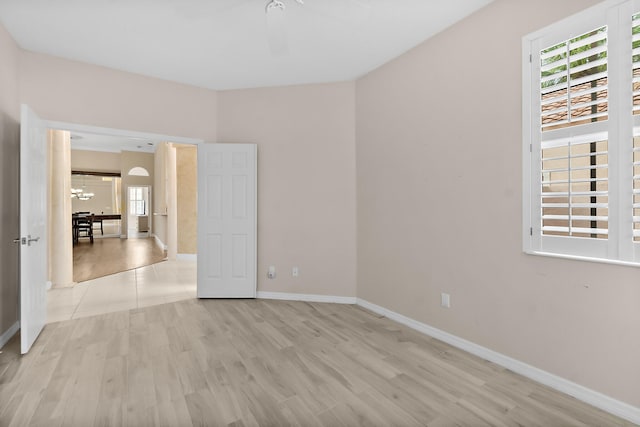 spare room featuring plenty of natural light, light hardwood / wood-style floors, and an inviting chandelier