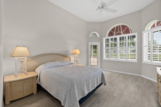 bedroom featuring hardwood / wood-style flooring, ceiling fan, and a towering ceiling