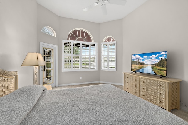 bedroom with ceiling fan, light hardwood / wood-style flooring, and high vaulted ceiling