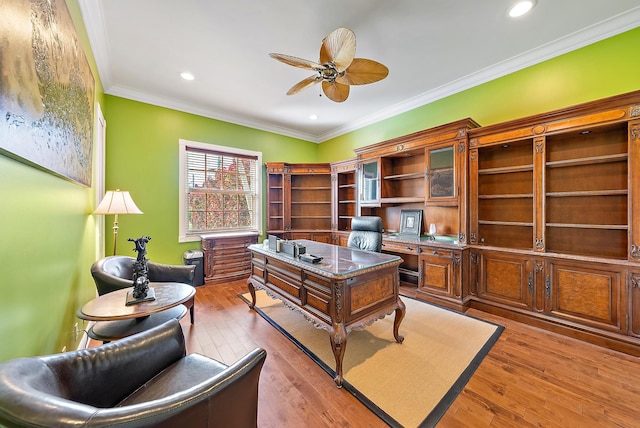 office featuring built in desk, light hardwood / wood-style flooring, ceiling fan, and ornamental molding