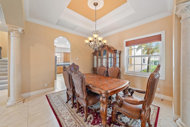 tiled dining area featuring a raised ceiling, ornamental molding, and a notable chandelier