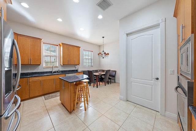 kitchen featuring sink, stainless steel appliances, a chandelier, decorative light fixtures, and a kitchen island