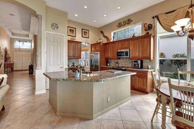 kitchen with a center island with sink, light tile patterned floors, sink, and appliances with stainless steel finishes