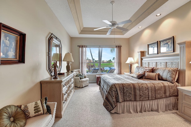 carpeted bedroom with a textured ceiling, a raised ceiling, and ceiling fan