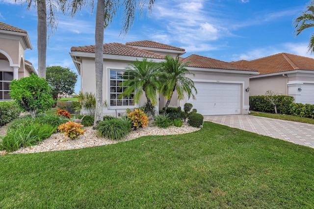 mediterranean / spanish home featuring a front yard and a garage