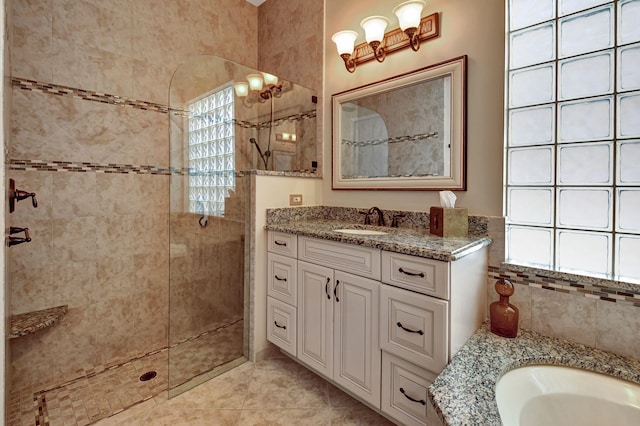 bathroom with tile patterned flooring, plenty of natural light, tiled shower, and vanity