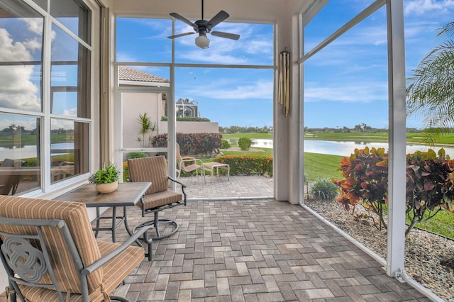 sunroom featuring ceiling fan and a water view