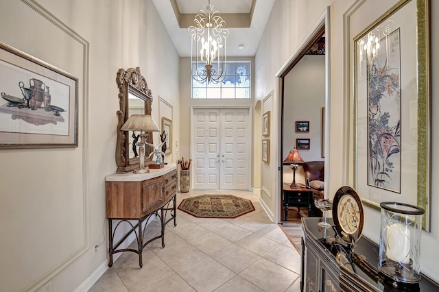 foyer featuring a towering ceiling, light tile patterned floors, and an inviting chandelier