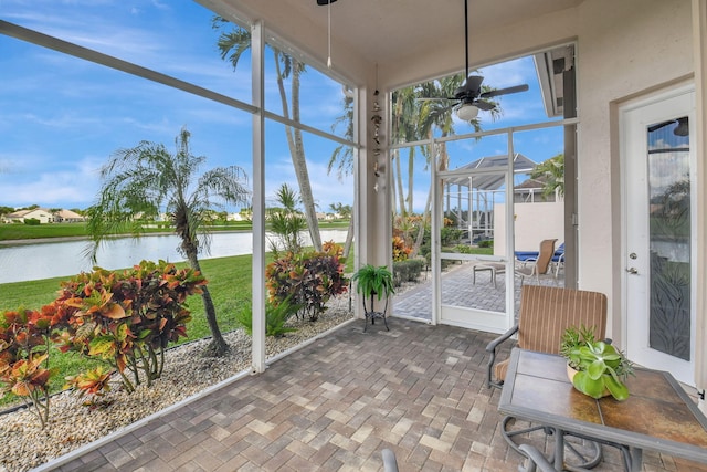 sunroom with ceiling fan and a water view