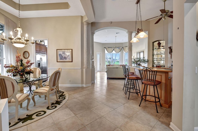 dining area with ceiling fan, light tile patterned flooring, and a towering ceiling