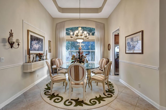 dining room with a raised ceiling, light tile patterned floors, and a notable chandelier