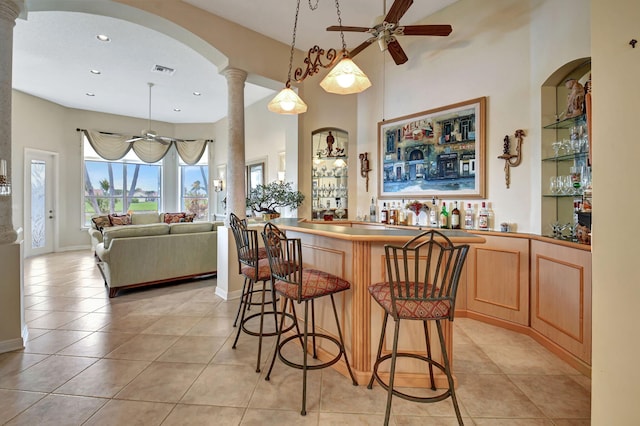 interior space with ceiling fan, ornate columns, hanging light fixtures, and light tile patterned floors