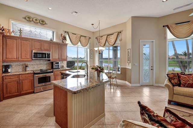 kitchen featuring decorative light fixtures, sink, stainless steel appliances, and plenty of natural light