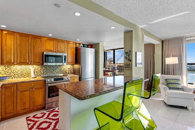 kitchen featuring stainless steel appliances, a kitchen island, plenty of natural light, and dark stone countertops