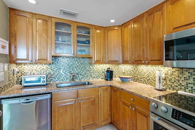 kitchen featuring light stone countertops, stainless steel appliances, tasteful backsplash, and sink