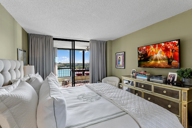 bedroom with access to exterior, floor to ceiling windows, and a textured ceiling