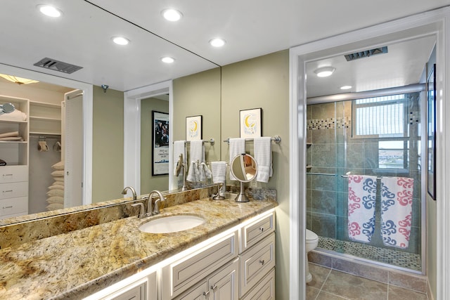 bathroom featuring tile patterned floors, a shower with door, vanity, and toilet