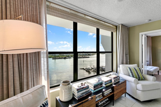 living area with light tile patterned floors, a water view, a textured ceiling, and a wall of windows